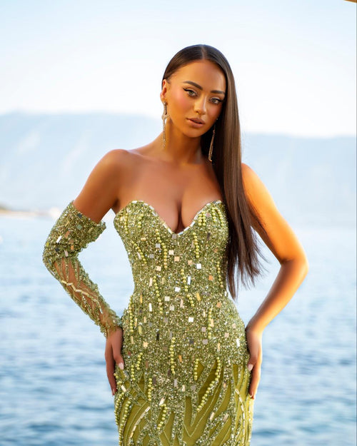 Woman in a sparkly gold dress standing by the water