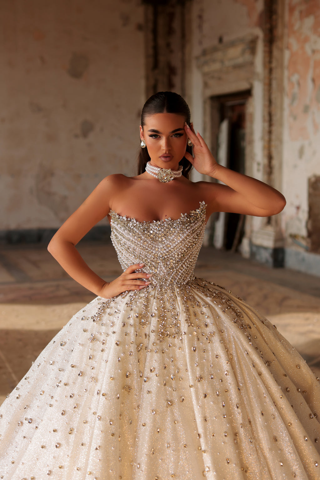 Woman wearing a sparkling gown in an indoor setting with textured walls.