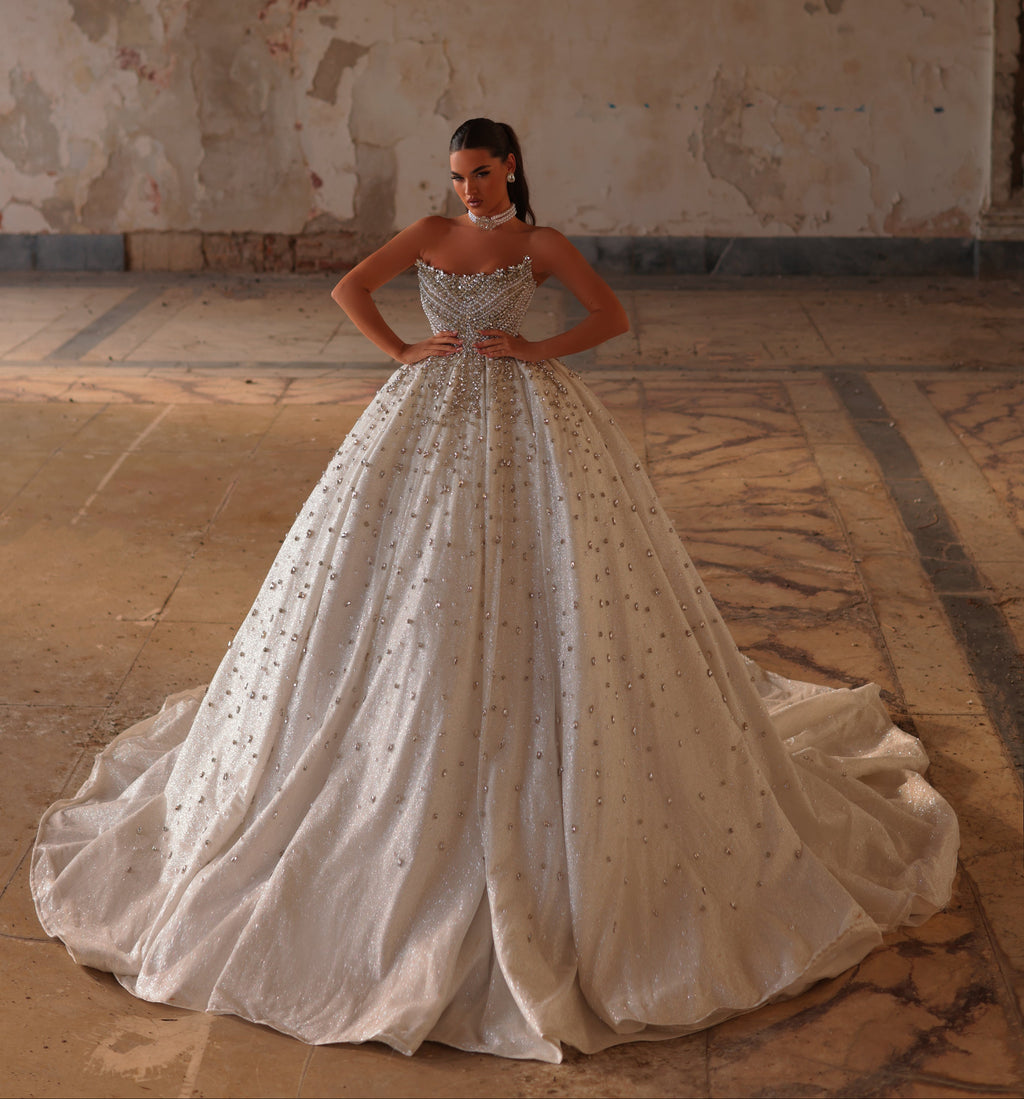 Woman in a white wedding dress standing in an old, textured room.