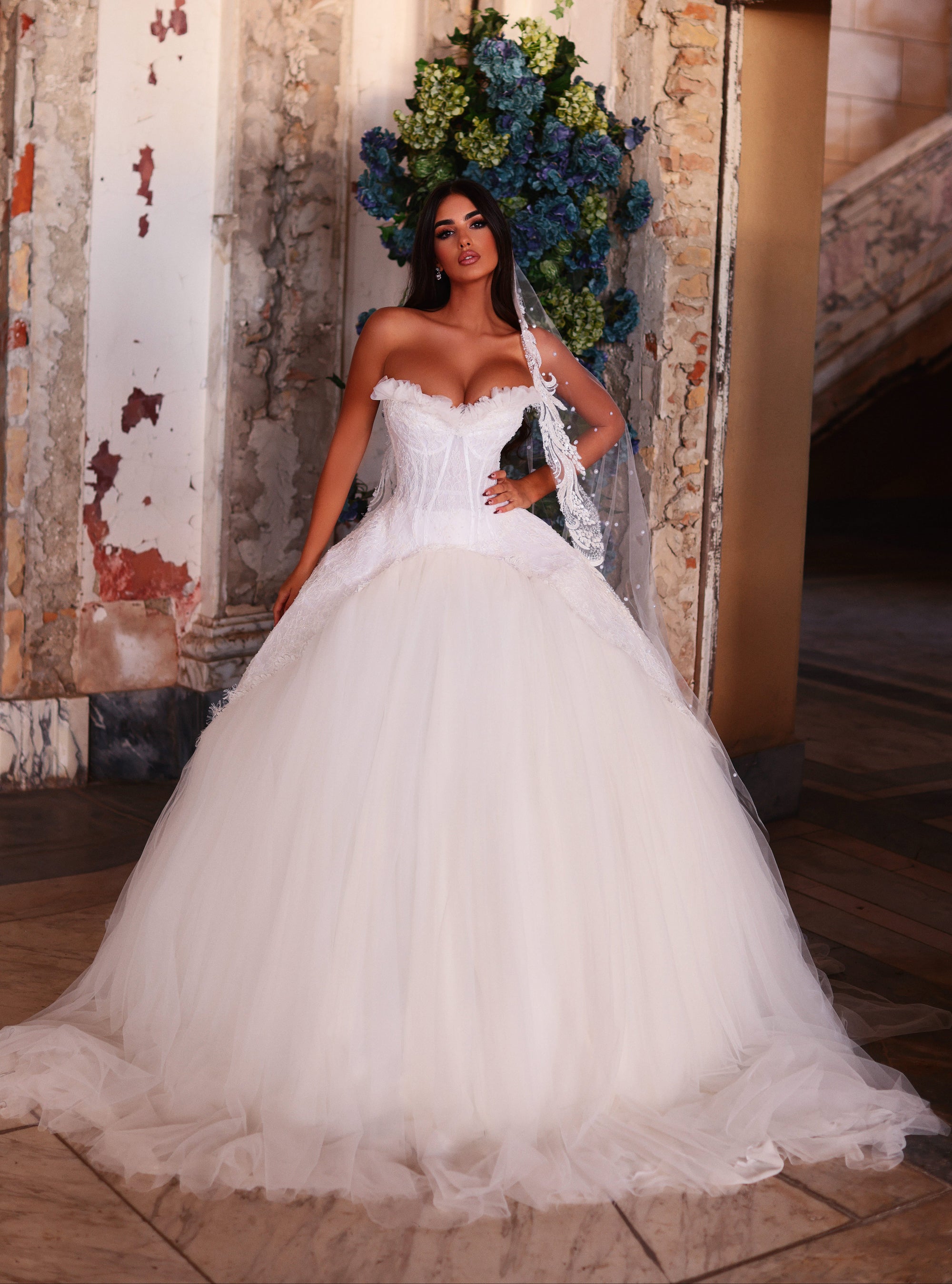 Woman in a white wedding dress standing in an elegant interior setting with decorative elements.