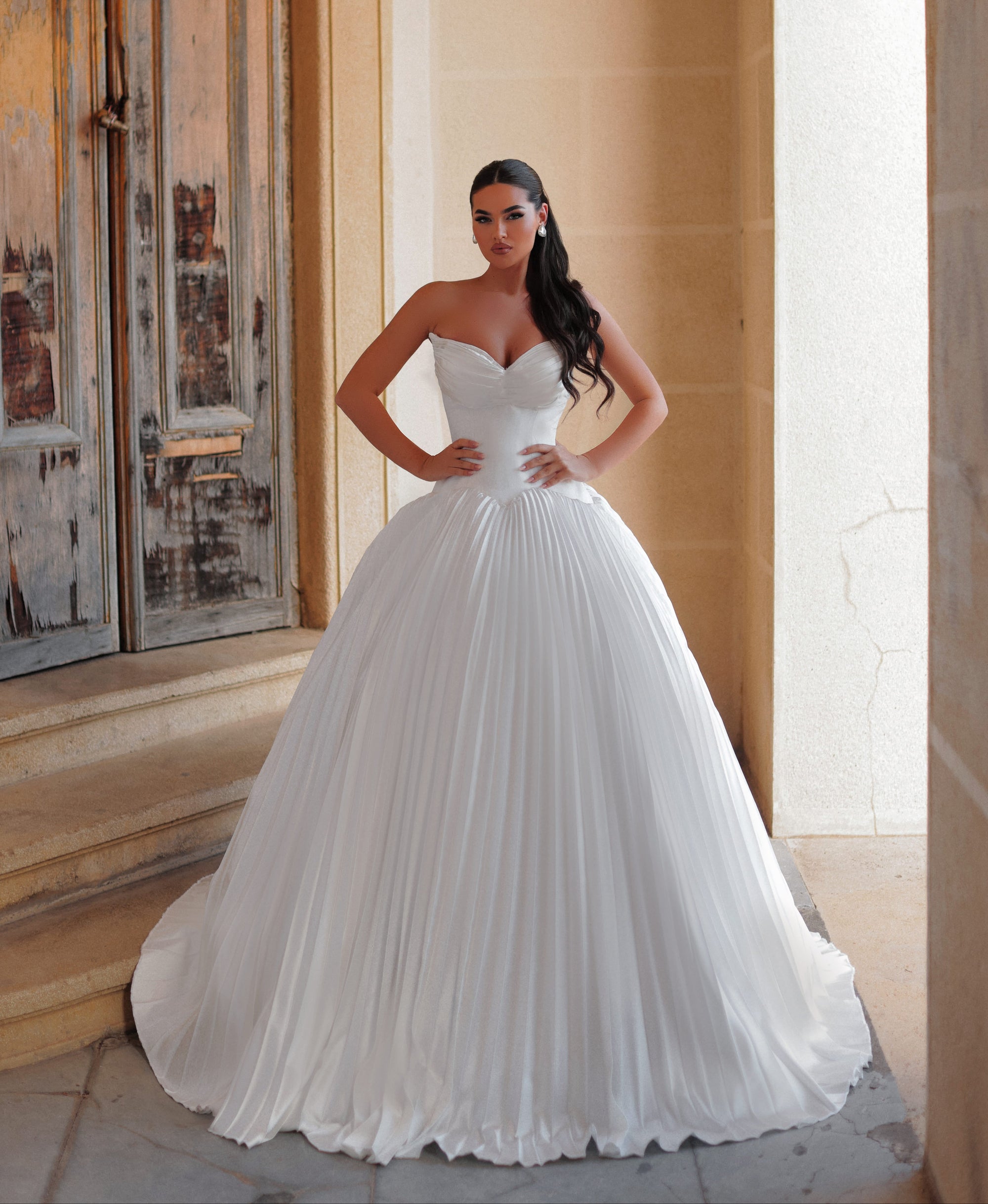Woman in a white wedding dress standing in an elegant interior setting.