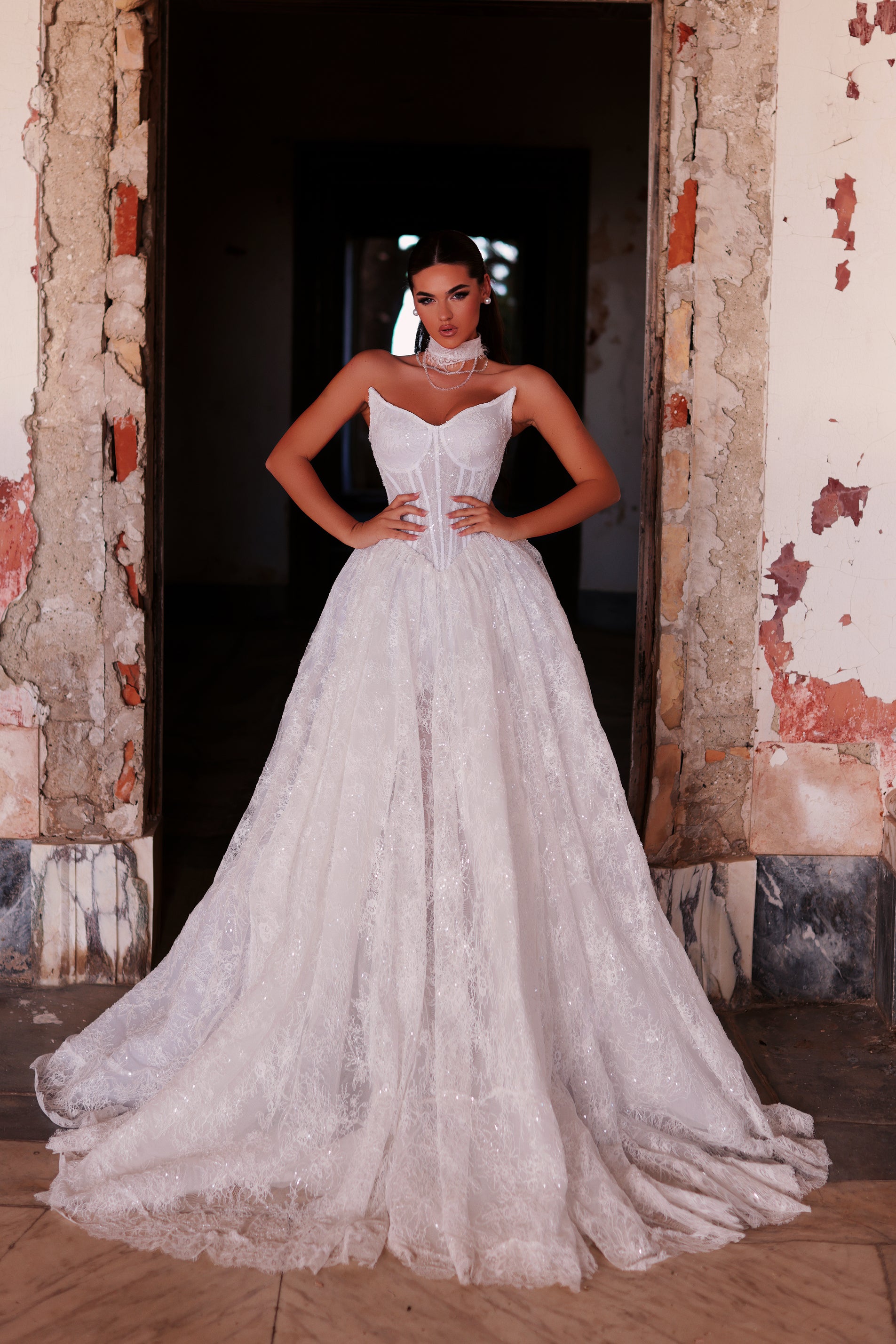 Woman in a white wedding dress standing in a doorway with peeling paint.