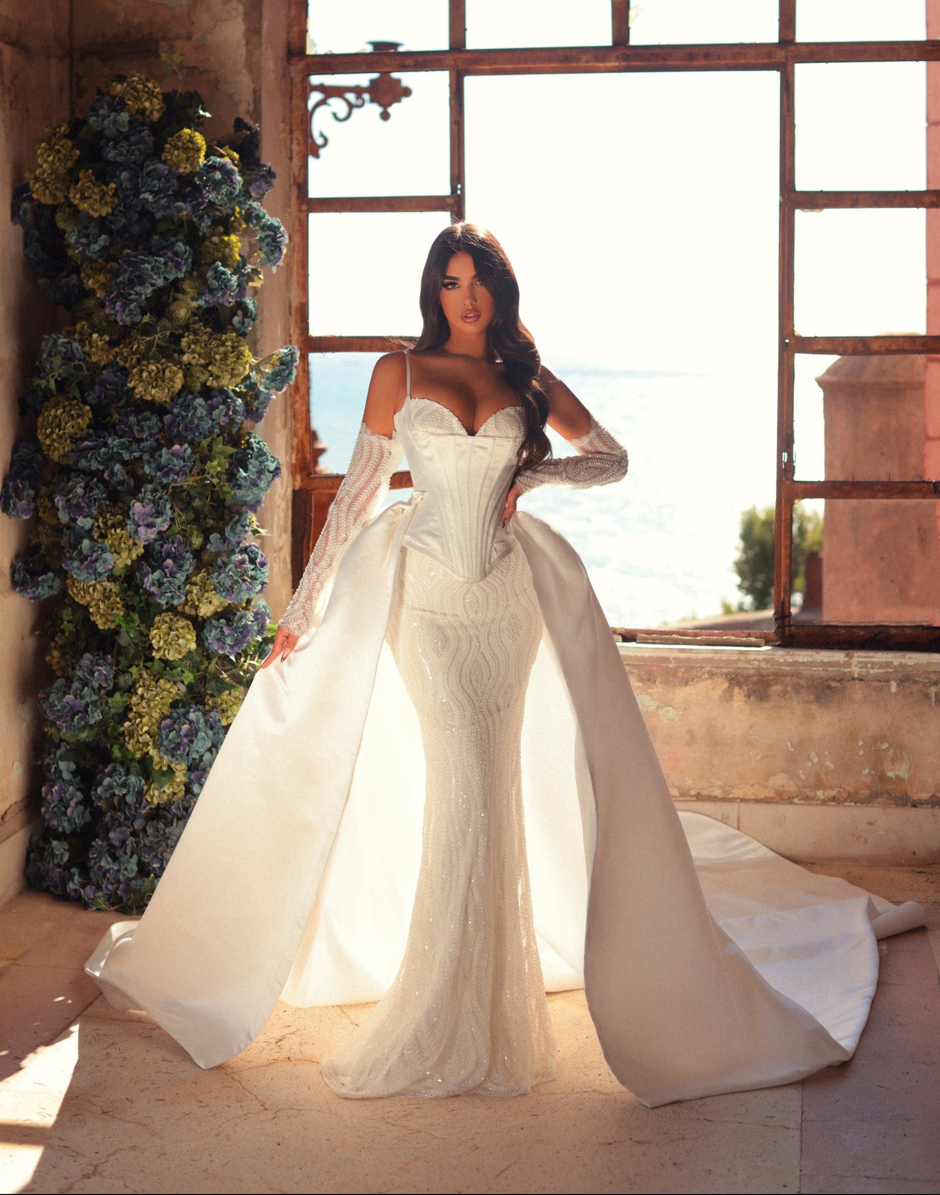 Woman in a white wedding dress standing in an outdoor setting with floral decorations.